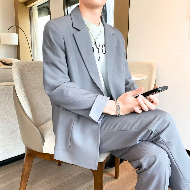 グレーのセットアップを着た男性が椅子に座って仕事する姿
