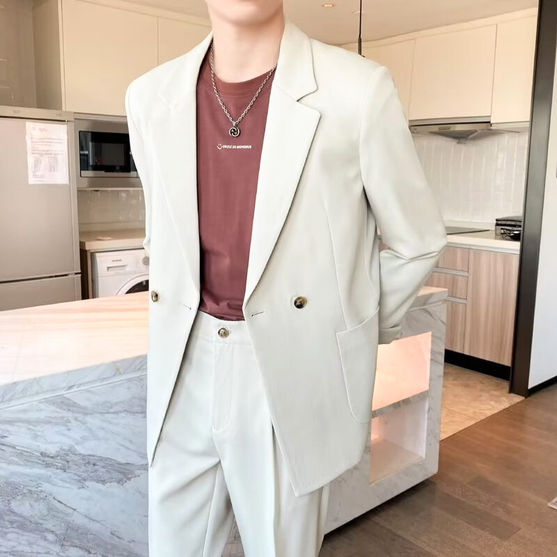 アイボリーのダブルボタンジャケットの前ボタンを開けてリラックスしている男性