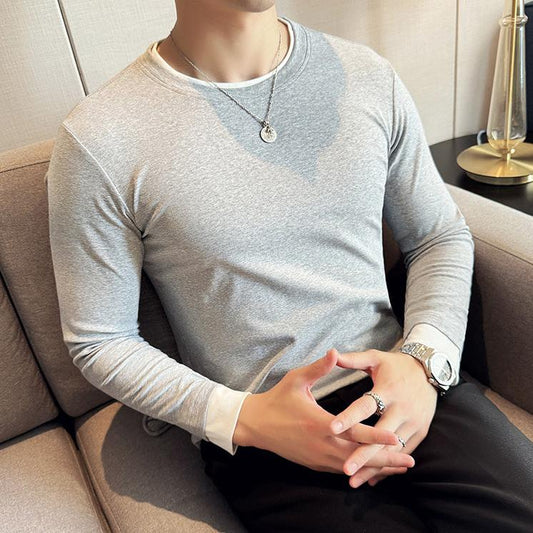 グレーのレイヤード風スリムTシャツを着た男性の座り姿