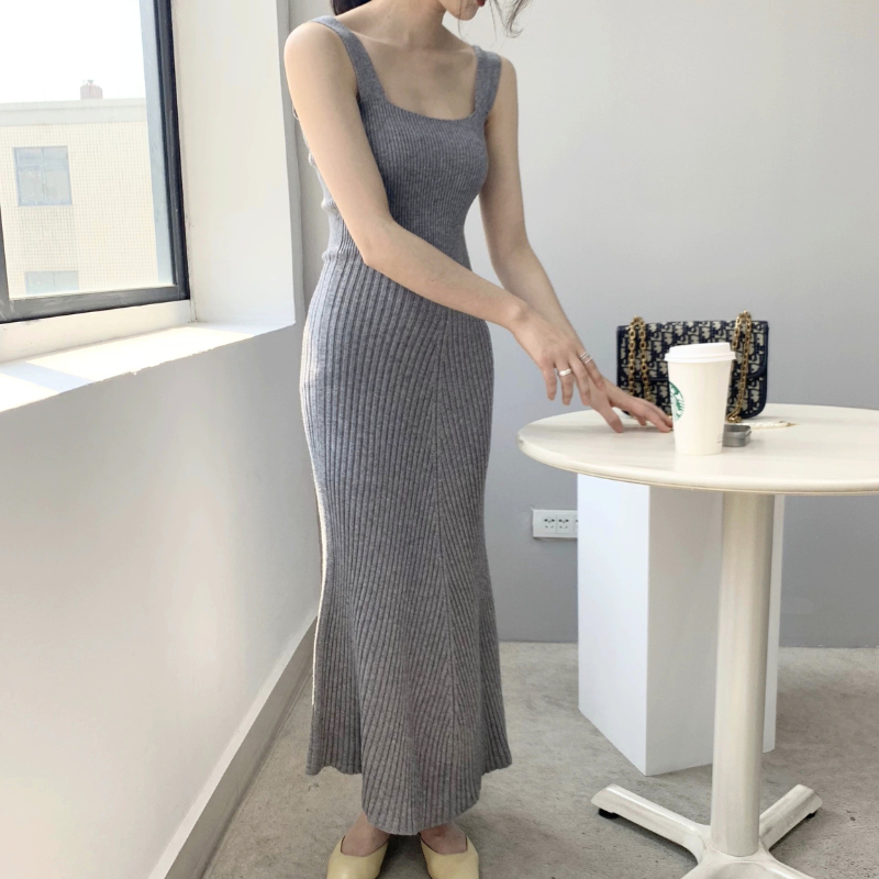 グレーのリブニットフレアワンピースを斜め前から着用。上身頃のフィット感とフレア裾が分かる写真