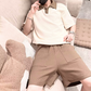 配色ポロとブラウンパンツのセットアップでソファに座る男性・夏のルームウェア提案