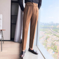 大きな窓を背景にしたスラックスの着こなし（ブラウン）