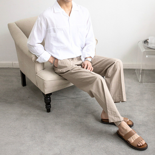 白シャツとベージュパンツでリラックスする男性（室内・着席）