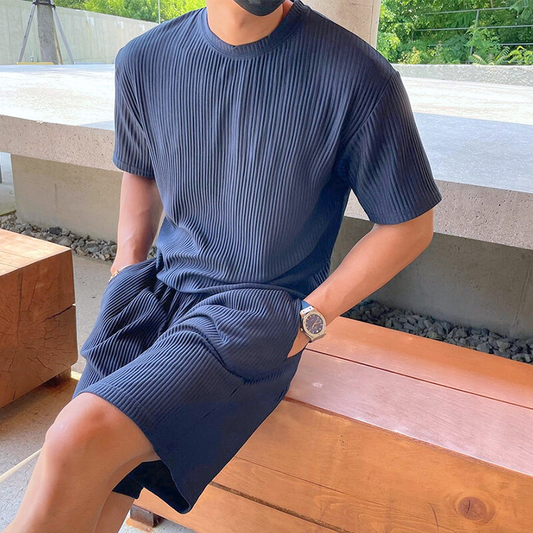ネイビーのリブセットアップを着た30代メンズがベンチに座っている様子