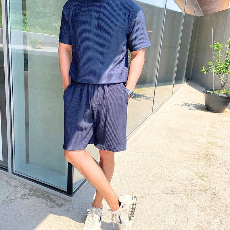 夏の屋外でネイビーのリブ素材セットアップを着こなす男性