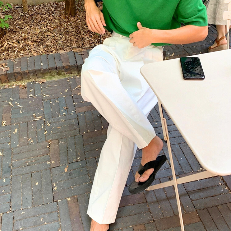 テーブル席でコーヒーを飲む男性が着用するリラックス感ある白パンツ
