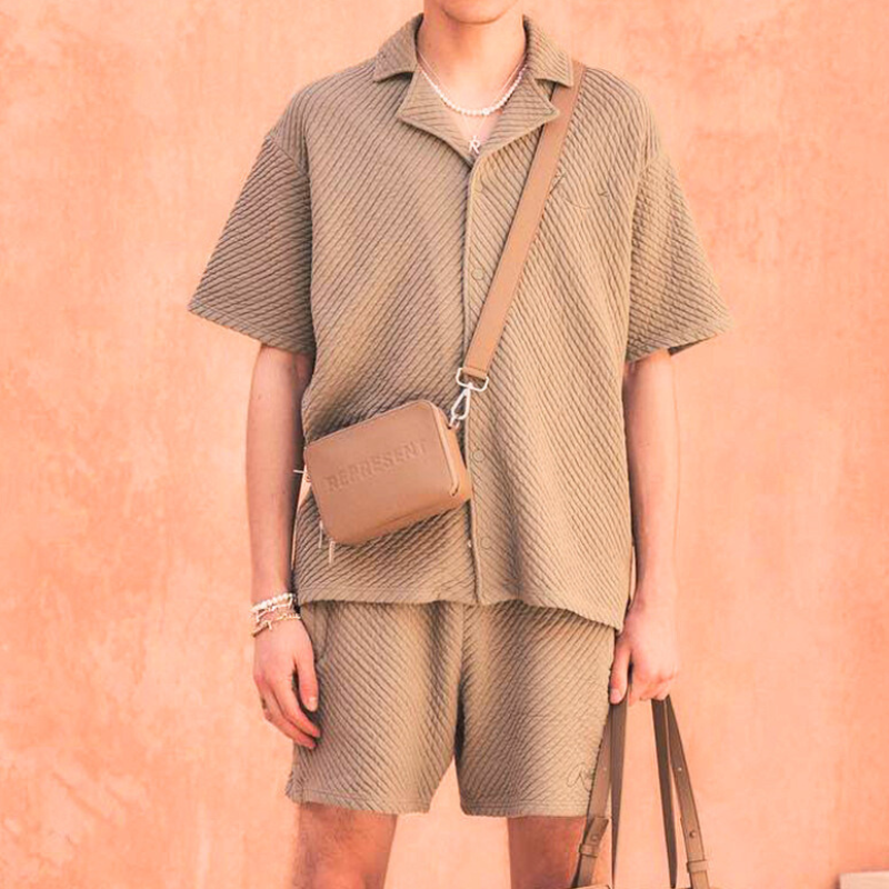 ベージュ系の凹凸素材開襟セットアップをバッグ合わせで見せたリゾート風メンズコーデ画像