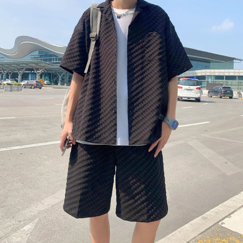 黒のセットアップを着た男性が空港の外でリラックスしたポーズ