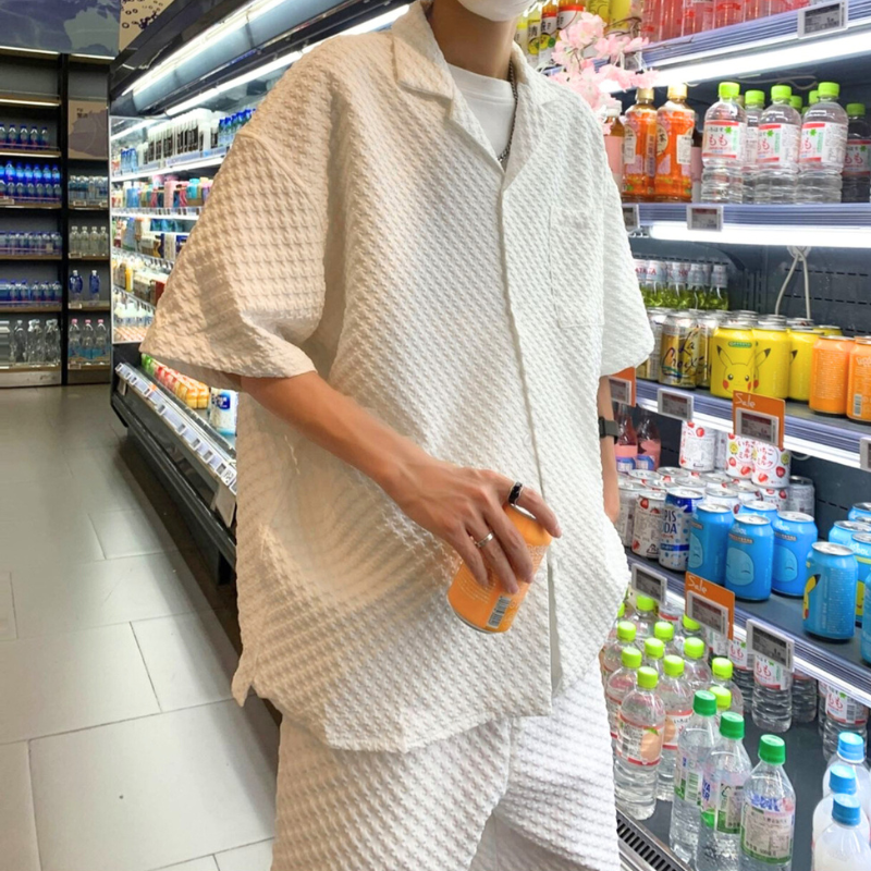 凹凸素材の白シャツセットアップを着た男性が商品棚の前で佇む