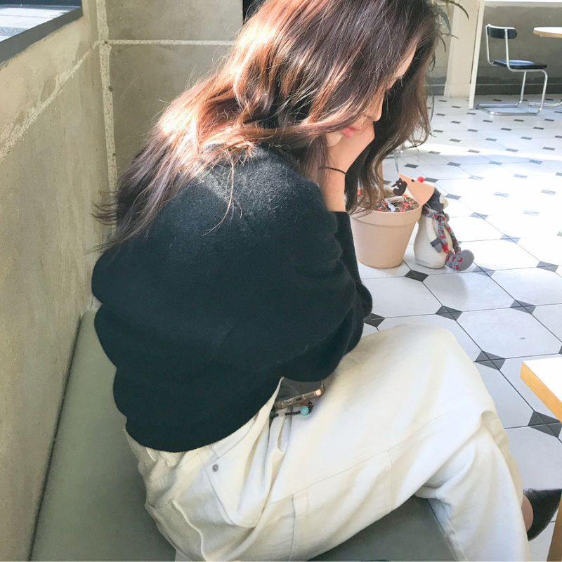 ブラックのオフショル風Vネックニットトップスを座って着用した画像