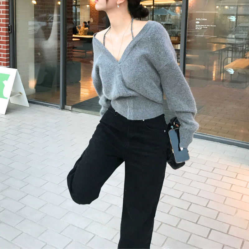 グレーのVネックニットトップスを着用した動きのある全身コーデ