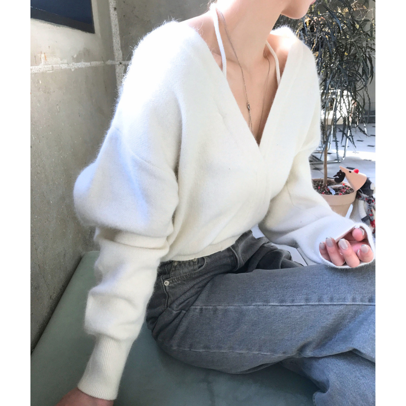 ホワイトのオフショル風Vネックニットトップスを座って着用したコーデ