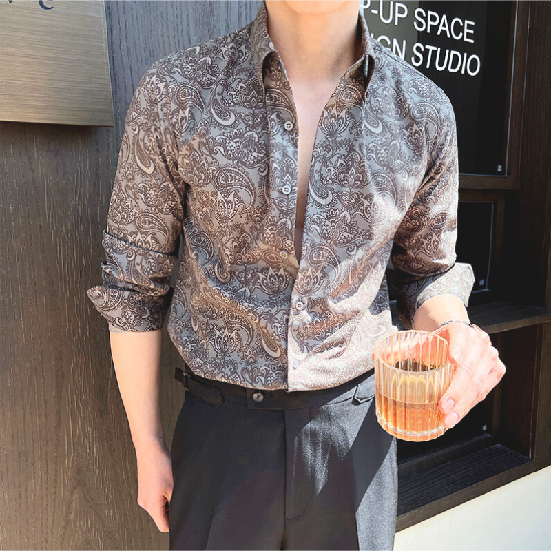 グレーのペイズリーシャツを着て正面を向く男性