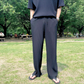 黒のプリーツセットアップで立ち止まる男性のフロント姿