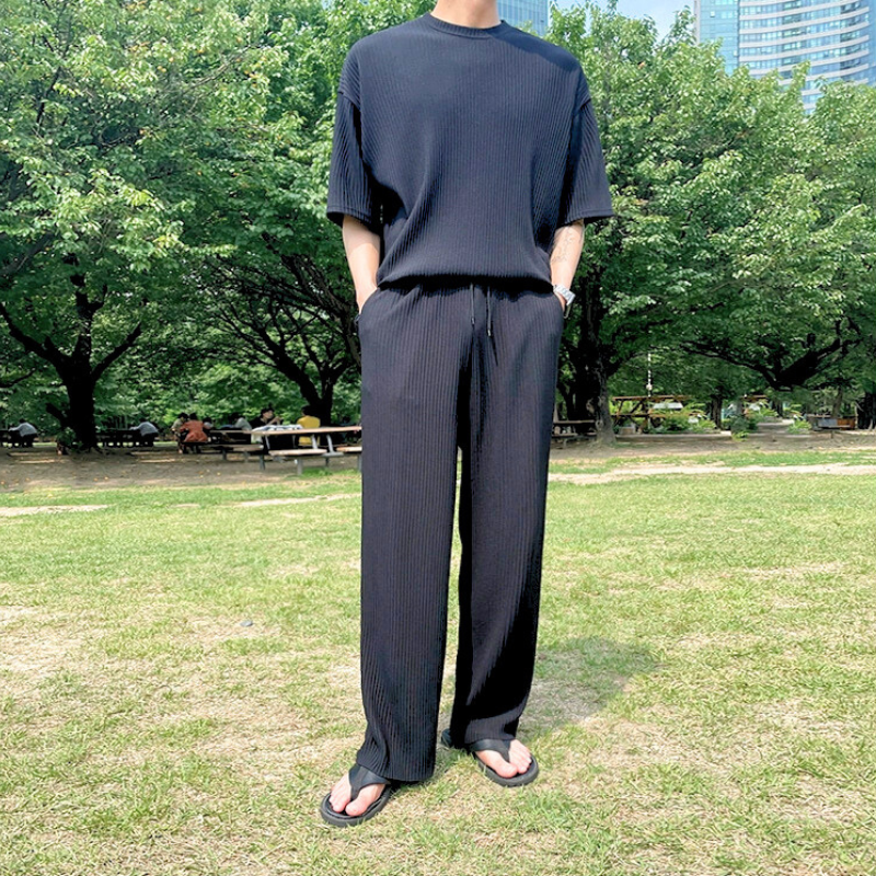 黒のプリーツセットアップ（ロングパンツ）を着た男性の全身スタイル