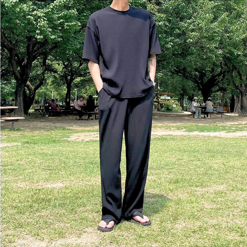 公園を歩く黒のロングパンツセットアップのスタイルカット