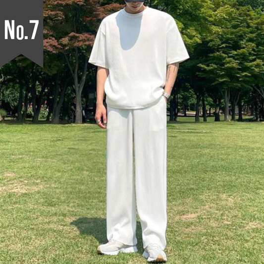 芝生の上で白のプリーツセットアップ（ロングパンツ）を着こなす男性