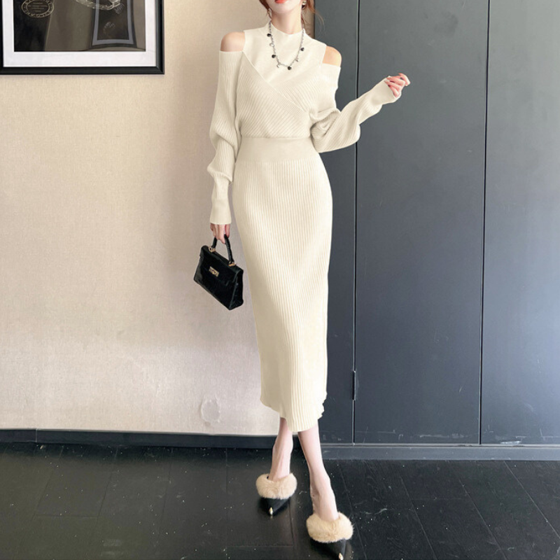 室内で立つ女性。ショルダーオープンのワンピースが上品に映える。