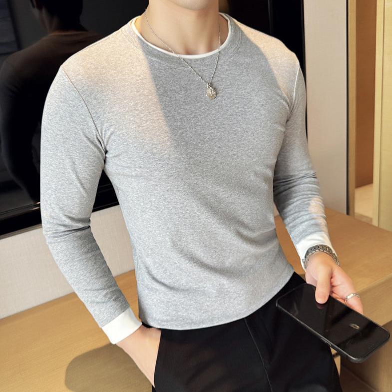 グレーのレイヤード長袖Tシャツを着た男性が横向きに立っている