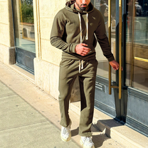 カーキ色のセットアップを外で着用している男性