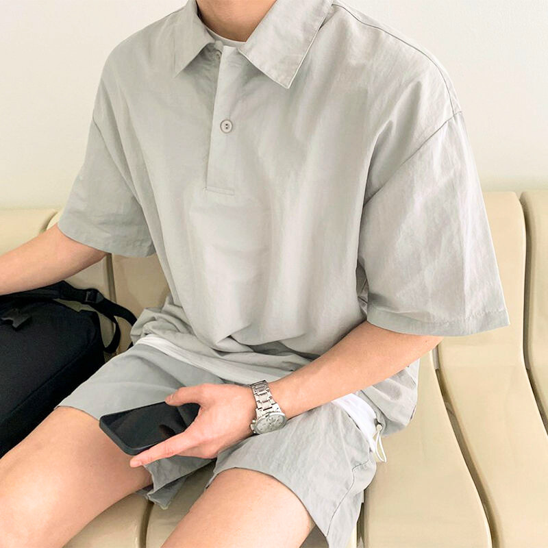 涼しげなグレーセットアップで座る男性の自然な着用シーン