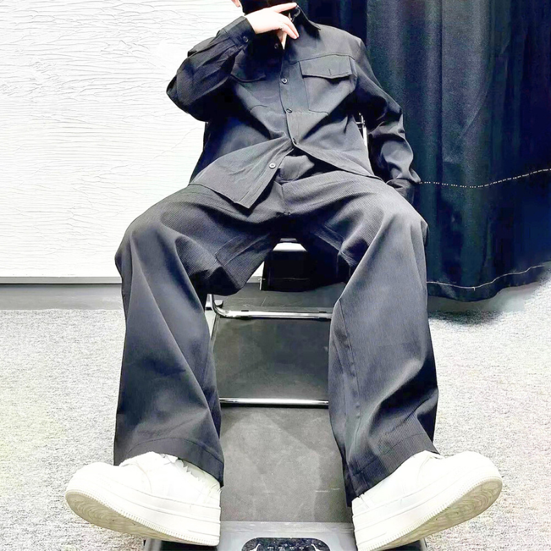 ブラックのセットアップを座った姿勢で見せる男性
