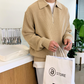 ベージュのジップリブニットを着てお店の前で撮影したシーン