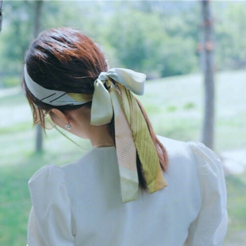 後ろ姿を撮影したホワイトブラウスで、パフスリーブとヘアアクセサリーが映える上品なシルエット